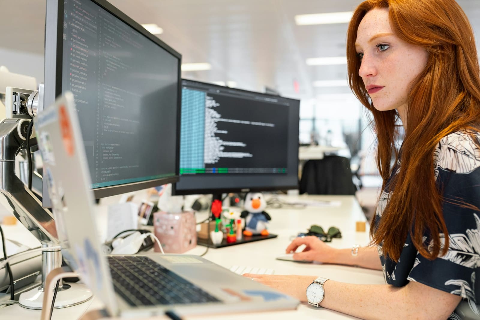 Una ingeniera revisando código en dos monitores